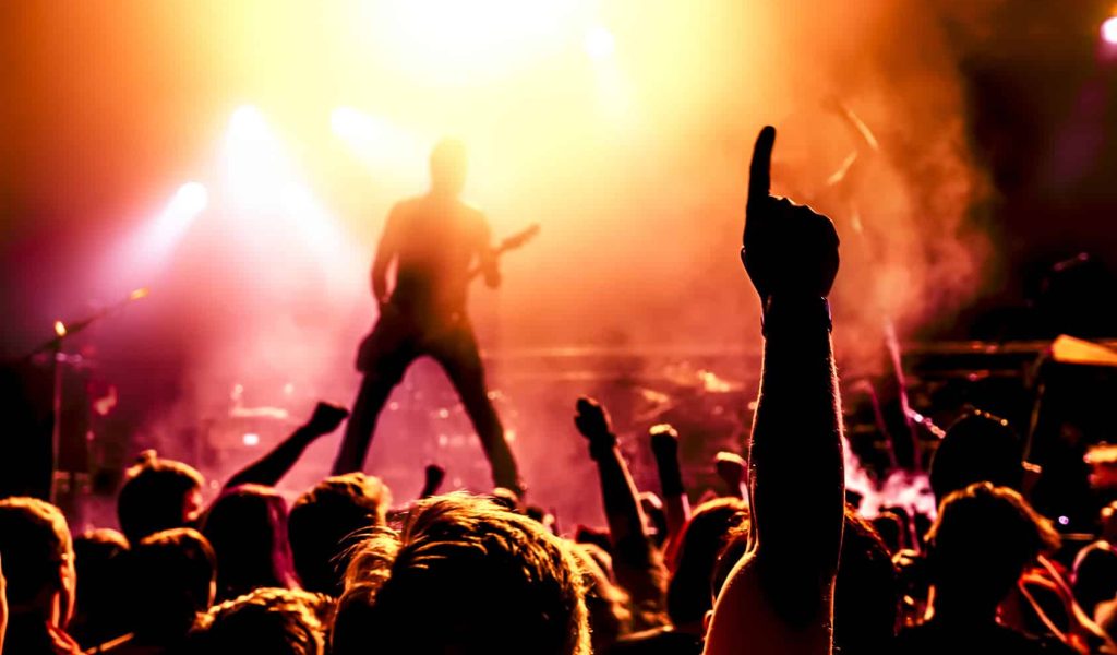 silhouette of guitar player in action on stage in front of concert crowd